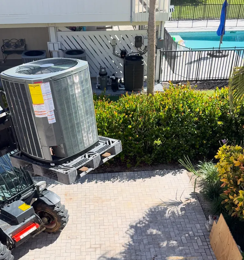 New condenser on a pallet being lifted into position by a compact loader