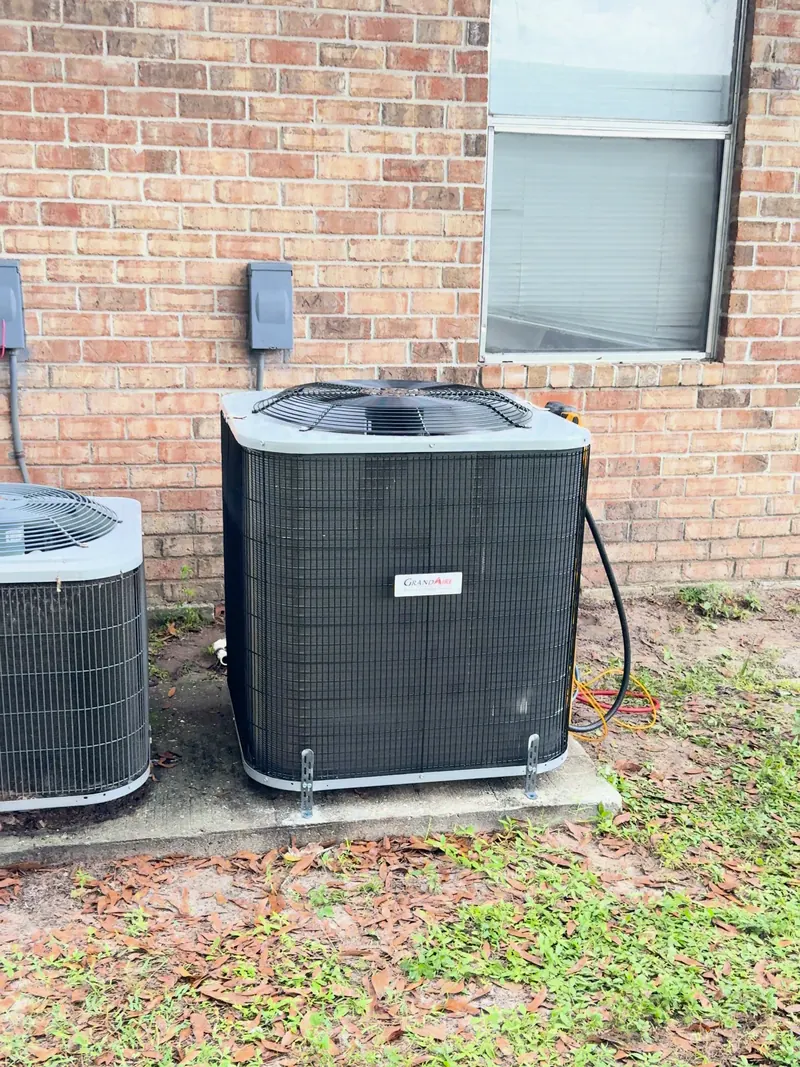 New condenser secured on a concrete pad next to a brick home